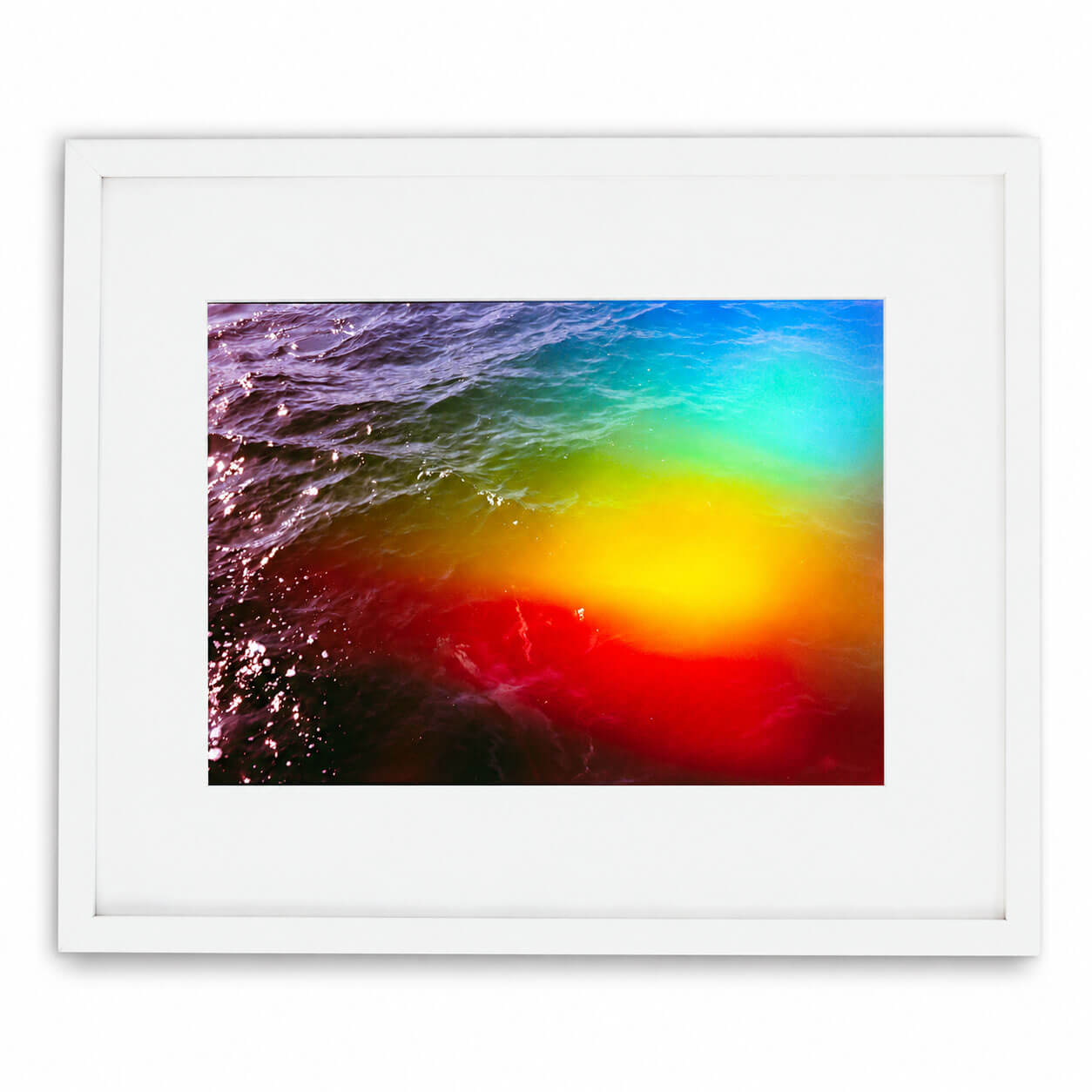 A framed art print featuring an abstract, colorful water scene with a gradient of red, yellow, green, and blue, presented in a white frame with a white mat against a clean white background.
